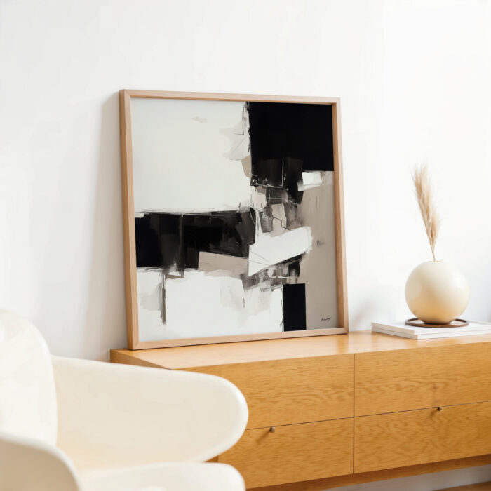 Abstract black and white artwork displayed on light wood console with minimalist decor.