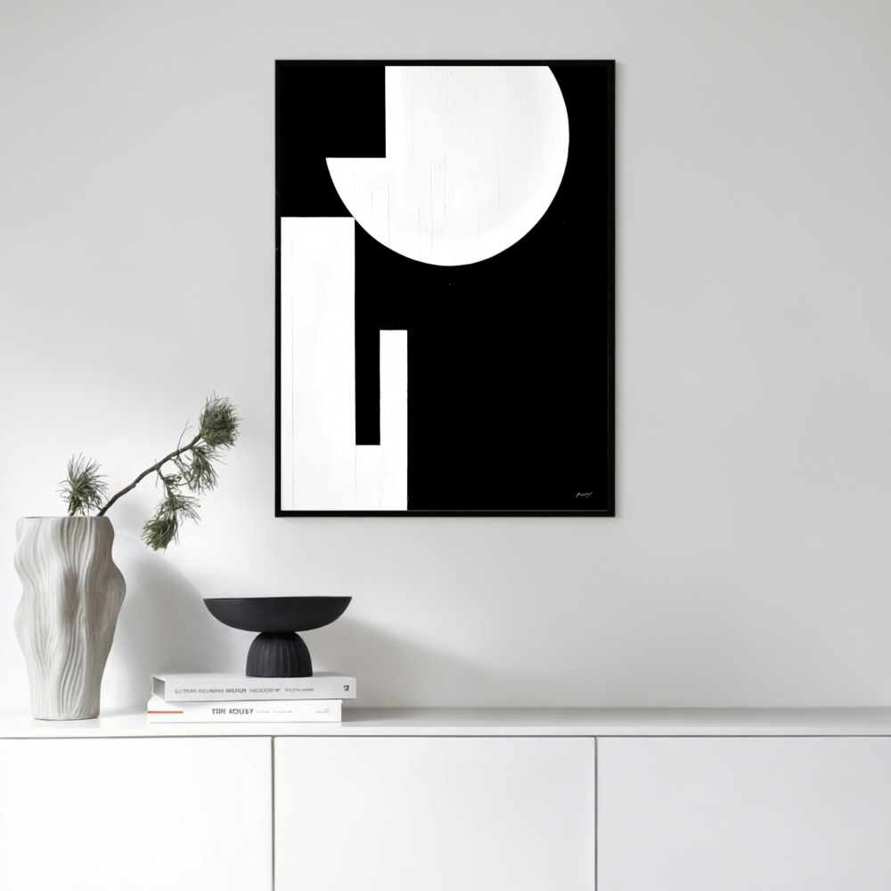 Minimalist black and white abstract art with circular form above modern white cabinet