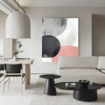 Modern minimalist living room with abstract circular artwork in white, black and coral tones.
