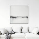 Minimalist black and white abstract art above white sofa in contemporary living space