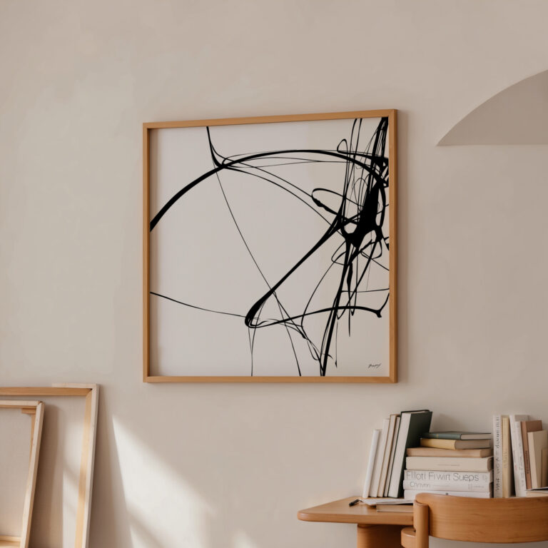 Minimalist black brushstroke abstract art in wooden frame on cream wall above books