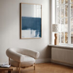 Minimalist blue and white abstract artwork hanging in a bright Scandinavian-style living room.