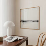Minimalist wooden desk with designer mushroom lamp, abstract black and white artwork, and open book.