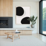 Minimalist living room with black circle art, wood panels and potted plant.