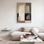 Minimalist living room featuring abstract neutral wall art above cream sofa and marble coffee table.