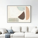 Abstract art with organic shapes in earthy tones above modern cream sofa.