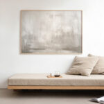 Serene abstract painting displayed above minimalist wooden bench with neutral cushion.