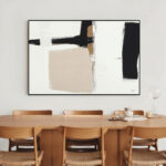 Black and white abstract art above warm wooden dining table and chairs
