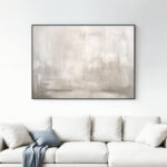 Elegant abstract artwork with soft gray tones displayed above minimalist white sofa.