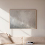 Abstract gray landscape artwork in wooden frame above cream sofa in minimalist interior