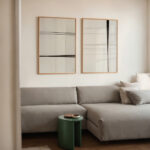Minimalist line art prints above gray sectional sofa in contemporary neutral living room.