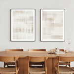 Abstract beige artwork above wooden dining table with curved chairs in warm space.