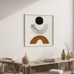 Minimalist abstract artwork with black circle and terracotta arch above wooden console table.