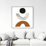 Minimalist geometric wall art with black circle and terracotta arch above white sofa.