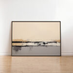 Minimalist abstract landscape artwork with beige horizon and dark gray shoreline in black frame.