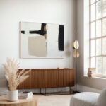 Minimalist living room featuring bold black and beige abstract art above wooden credenza.