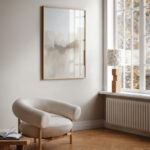 Neutral abstract art print in serene minimalist room with cozy armchair and natural light.