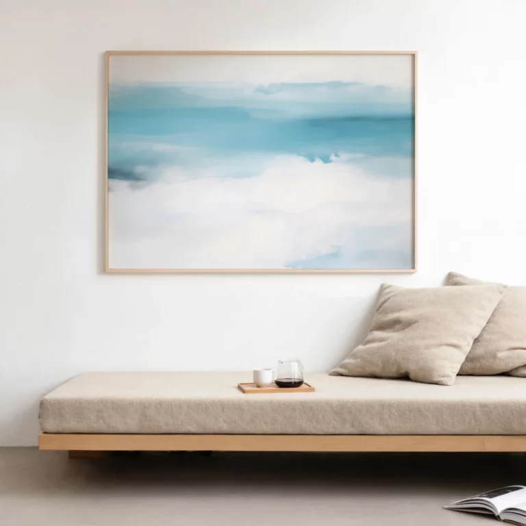 Minimalist coastal artwork above wooden bench in serene blue and white interior.