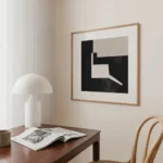 Minimalist workspace with abstract black and white artwork and mushroom lamp.