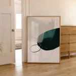 Abstract teal and black artwork leaning against wall in minimalist interior space.