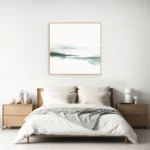 Minimalist bedroom with white bedding, wooden accents and abstract teal artwork.