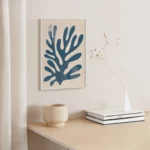 Abstract blue coral artwork above wooden shelf with minimalist decor.