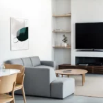 Minimalist contemporary living room with gray sofa, wooden furniture and abstract wall art.
