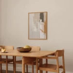 Minimalist wooden dining table with chairs and fruit bowl beneath abstract wall art.