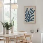 Bright minimalist Scandinavian dining room with wooden table and blue coral artwork.