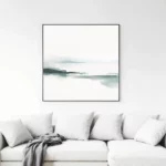 Minimalist watercolor artwork above white sofa with gray throw blanket.