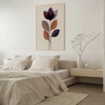 Framed abstract flower art print with layered purple and brown shapes, hung above a light bed with neutral bedding and a wooden bedside table in a modern bedroom.