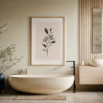 Framed black and white botanical branch art print, displayed on a light wall above a modern beige freestanding bathtub in a serene minimalist bathroom.