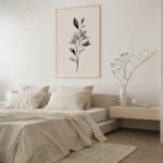 Framed black and white botanical branch art print on a blush background, hung above a light bed with neutral bedding in a modern minimalist bedroom.
