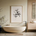 Framed black and white minimalist line art print of a leafy sprig with solid black leaves, hung on a light wall above a modern beige freestanding bathtub in a minimalist bathroom.