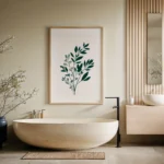 Framed art print of a dark green botanical sprig on a light background, displayed on a wall above a modern freestanding beige bathtub in a serene minimalist bathroom.