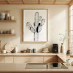 Framed black and white minimalist cactus line art print, adorning a light wall above wooden kitchen cabinets and a sleek countertop in a modern kitchen.