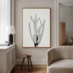 Monochrome minimalist cactus line drawing framed art, displayed above a side table with a lamp and armchair in a cozy living room reading nook.