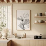 Framed minimalist line drawing of a fiddle leaf fig, hanging on a neutral wall above a wooden shelf and counter in a modern kitchen setting.