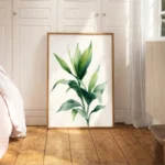 Large framed art print of a green leafy plant branch, leaning on a light wooden floor against a white wall with wainscoting, in a bright minimalist bedroom.