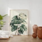 Large framed art print of a Monstera plant, leaning on a wooden floor against a white wall, complemented by warm-toned terracotta pots and vases, creating an inviting space.