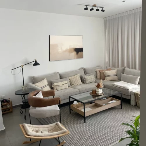 Modern minimalist living room with neutral sectional sofa and abstract wall art.